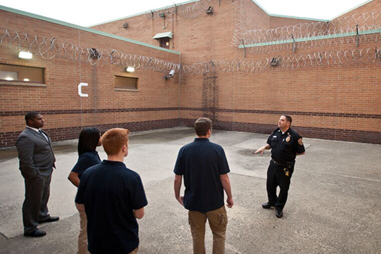 Captain Joe Interrante with Montgomery County corrections tours a group of cadet explorers from the Montgomery County District Attorney's office through an outdoor exercise area lined with razor wire at the Montgomery County Correctional Facility in Eagleville. Detective Tyrone Tate, left, runs the explorer program. ( RON TARVER / Staff Photographer )