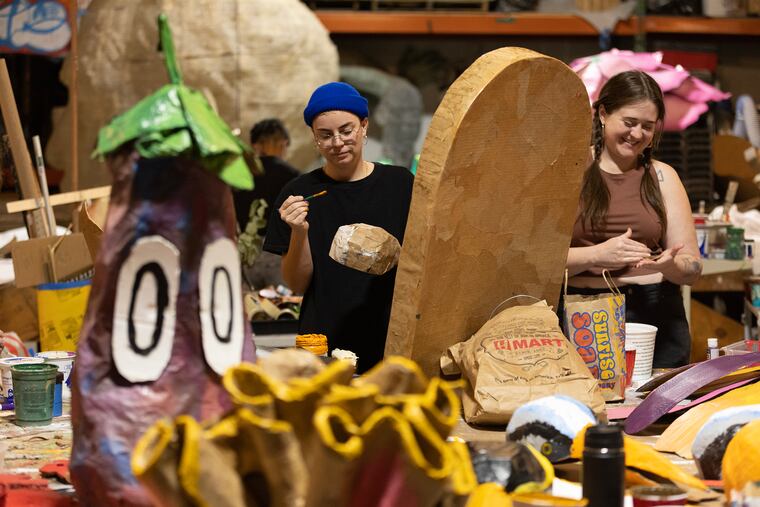 Vic Fulton (left) and Lizzie Gordon work to paint props for the Peoplehood Parade, which will march through West Philadelphia on Saturday.