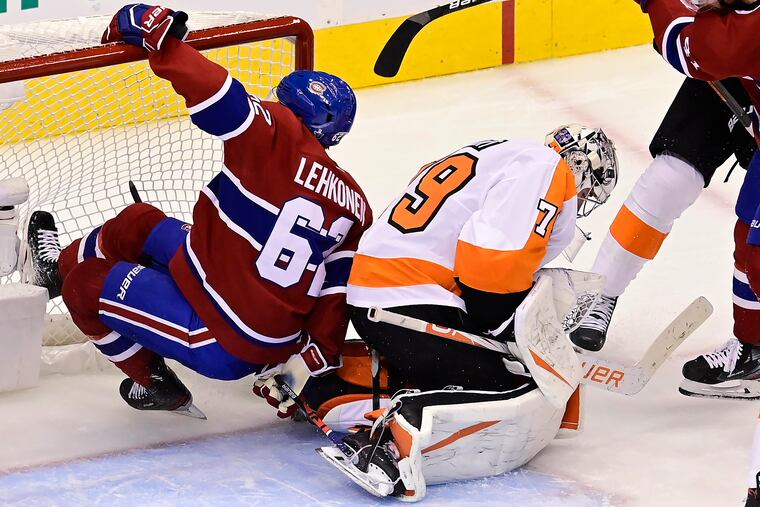 Carter Hart makes a save as Montreal's Artturi Lehkonen crashes into the net during Sunday's playoff game in Montreal.