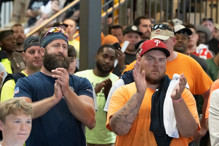 Construction union workers Tyler Hecht, (right) and Chris Condrone (left) applaud during a June construction union rally in support of the Sixers arena proposal at the new IBEW Local 98 headquarters in Philadelphia.