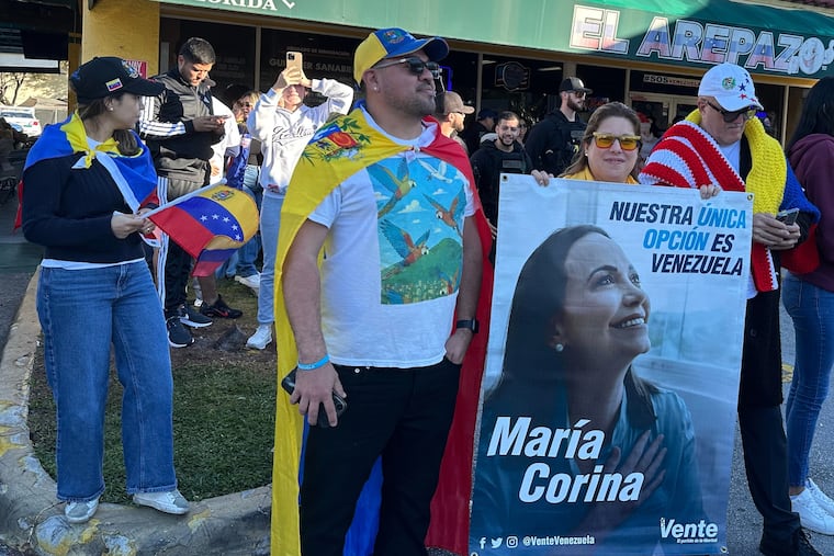 From left, Venezuelans David Nuñez, Lisbeth Garcia, Victor Gimenez gather outside El Arepazo restaurant with a banner of opposition leader and Nobel Peace Prize winner Maria Corina Machado amid celebrations following news of Venezuelan President Nicolás Maduro capture in Doral, Fla., on Saturday, Jan. 3, 2026.