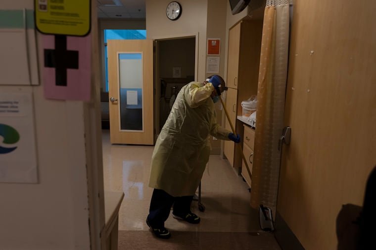 An environmental technician cleans a room after a COVID-19 patient was transferred to an intensive care unit at Providence Holy Cross Medical Center in Los Angeles.