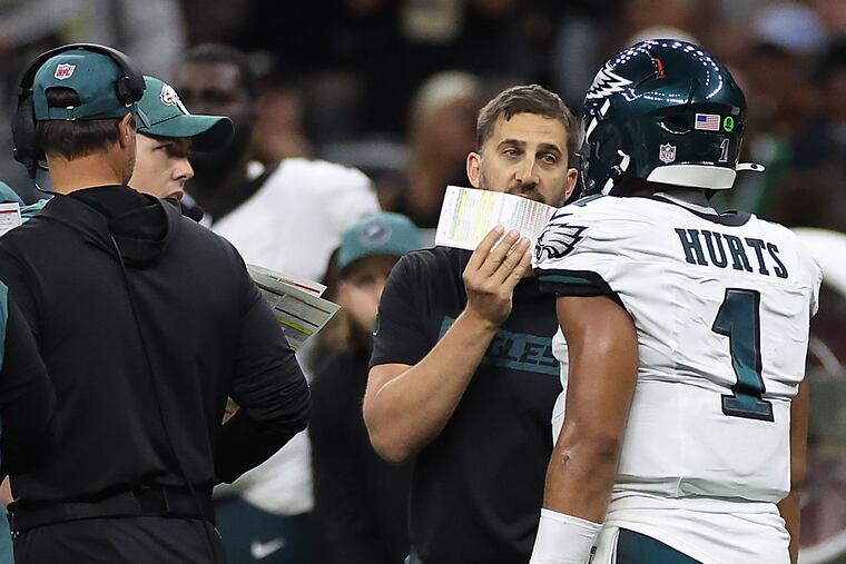 Eagles coach Nick Sirianni talks with quarterback Jalen Hurts during a timeout against the Saints as offensive coordinator Kellen Moore (left) looks on.