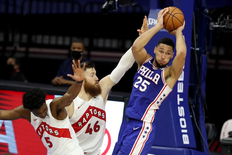 Ben Simmons, right, of the SIxers passes to a teammate after the Stanley Johnson, left, and Aron Baynes of the Raptors converge upon him during the 2nd half of a NBA game at the Wells Fargo Center on Dec. 29, 2020.