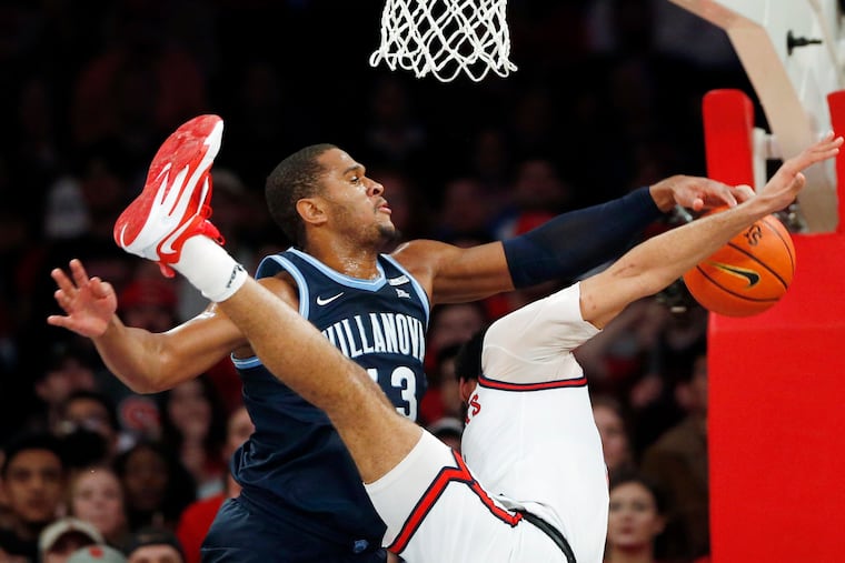 Villanova forward Eric Dixon defends as St. John’s guard Julian Champagnie takes a tumble during the first half in New York.