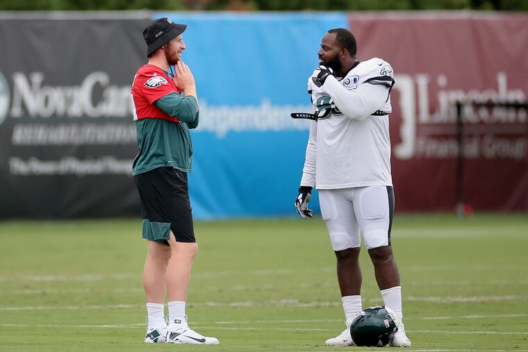 Carson Wentz (left) confers with Fletcher Cox during Tuesday's practice at the NovaCare Complex .