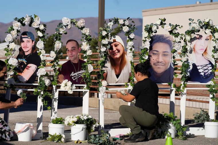 Noah Reich, left, and David Maldonado, the Los Angeles co-founders of Classroom of Compassion, set up a memorial near Club Q in Colorado Springs, Colo., in 2022 with photographs of the five victims of a mass shooting at the gay nightclub.
