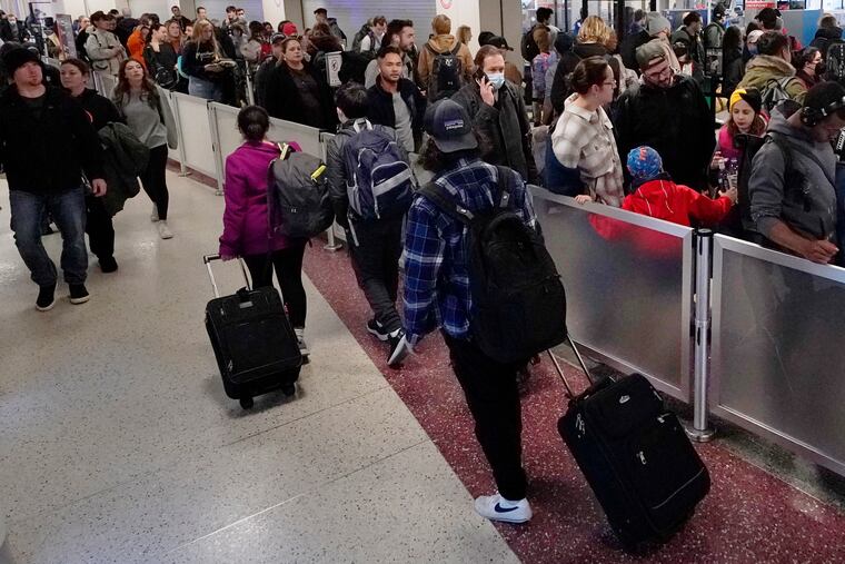 Travelers wheel the bags past the line for TSA screening in Terminal B at Logan International Airport on Monday in Boston.
