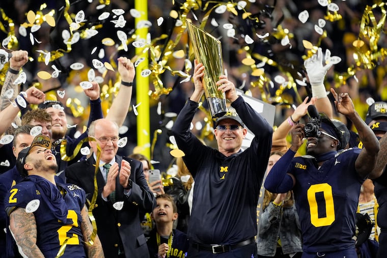 Michigan coach Jim Harbaugh celebrates with the trophy after beating Washington to win in the national championship on Monday in Houston.