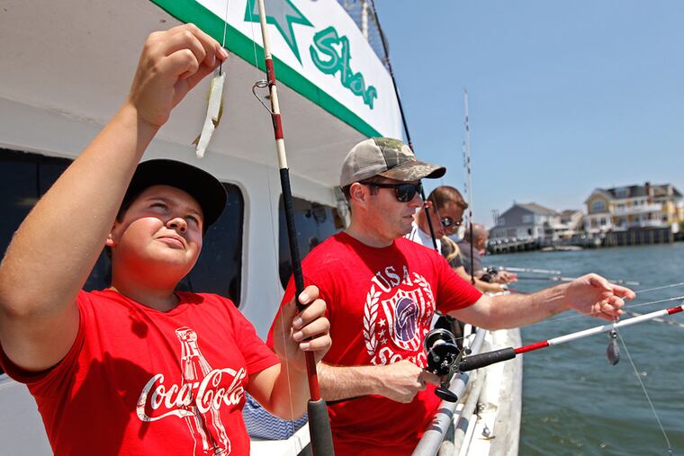 Alex Szawlewicz, 12, of Moorestown, baits his hook with a squid strip and a minnow as he prepares to drop his line over the side of the North Star fishing boat in the bay area of Ocean City. (Michael Bryant / Staff Photographer)