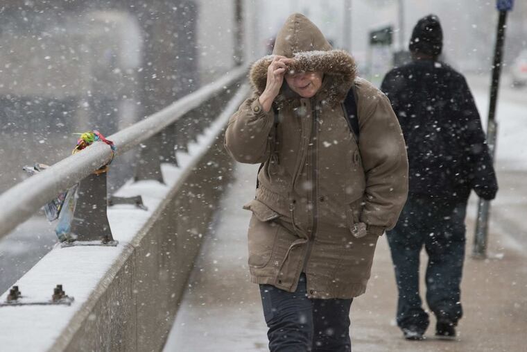 Pedestrians fight the wind and snow on Walnut Street.