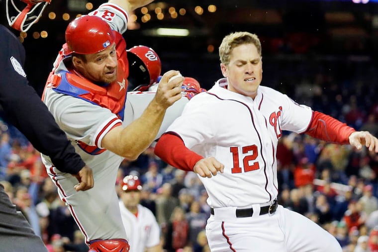Philadelphia Phillies catcher Erik Kratz (31) hangs on to the ball to make the tag on Washington Nationals' Tyler Moore (12) for the out at home during the fourth inning of a baseball game at Nationals Park, Friday, May 24, 2013, in Washington. (AP Photo/Alex Brandon)