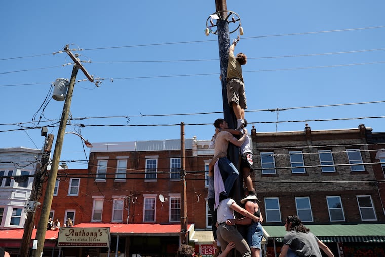 Doyle DiStefano reaches for the top of the grease pole at the South 9th Street Italian Market Festival on Saturday.