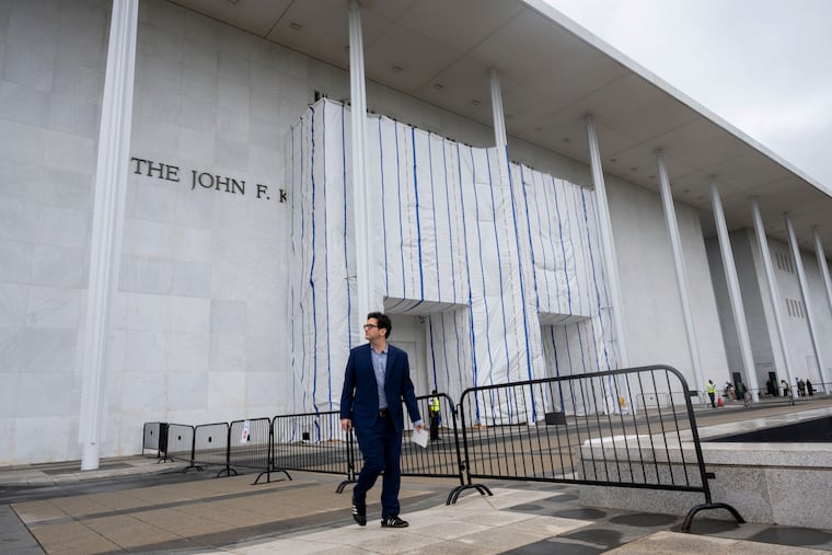 People walk near the tarp covered front entrance of the Kennedy Center for the Performing Arts on Sunday in Washington.