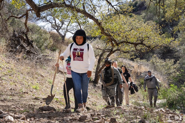 The Searching Mothers of Sonora, flanked by Mexico law enforcement, walk through a canyon during their search for Nancy Guthrie on Wednesday in Nogales, Mexico.