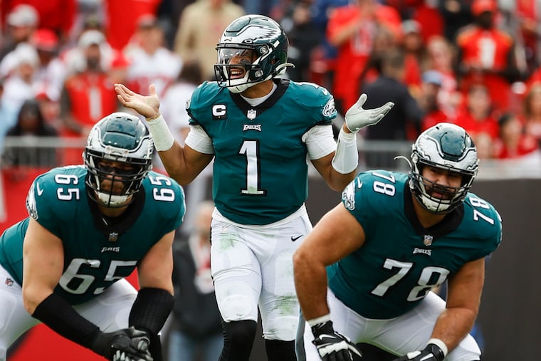 Eagles quarterback Jalen Hurts raises his arms with teammate offensive tackle Lane Johnson and guard Sua Opeta against the Tampa Bay Buccaneers during the second quarter in a NFC Wildcard playoff game on Sunday.