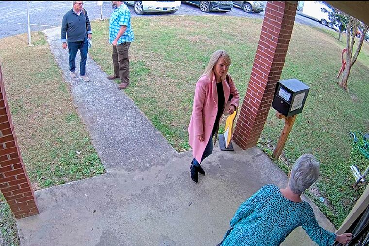 In this Jan. 19, 2021 image taken from Coffee County, Ga., security video, Cathy Latham, bottom, who was the chair of the Coffee County Republican Party at the time, greets a team of computer experts from data solutions company SullivanStrickler at the county elections office in Douglas, Ga. Records show that the team traveled to the rural south Georgia county to copy software and data from elections equipment. The Georgia secretary of state's office has said the visit was an "alleged unauthorized access" of election equipment. (Coffee County via AP)