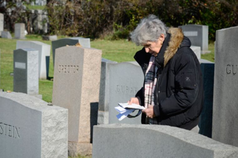 Joan Keyser places a stone on the grave of a relative in Mount Jacob Cemetery in Glenolden, Delaware County. (Ron Tarver / Staff Photographer)