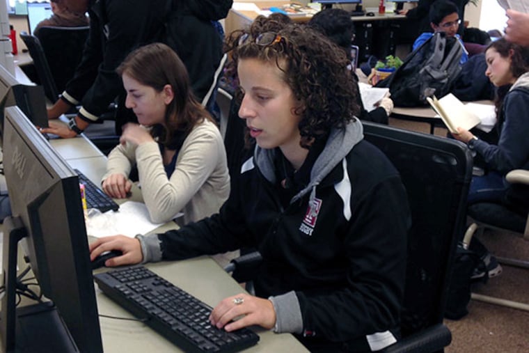Bailey Fuentes (foreground), a Temple University senior, looks at evaluations for a professor she will have in the spring. (Susan Snyder/Staff)