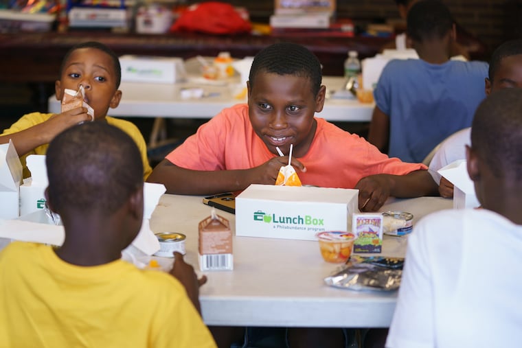Sabre Washington, 7, left, Hytheem Fielder, 13, center, eat lunch provided by Philabundance at the Ford Police Athletic League Center in South Philadelphia. Summer is the hungriest time of year for Philly kids, since they're not eating breakfast and lunch in school.
