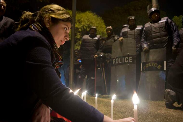 Outside a mosque in Islamabad , police stand guard during a rallyas a participant lights a candle in memory of the students killed in Tuesday's attack. B.K. BANGASH / Associated Press