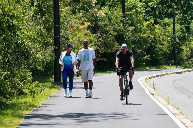 Walkers and a biker use the newly paved recreation path/sidewalk on Martin Luther King Drive.