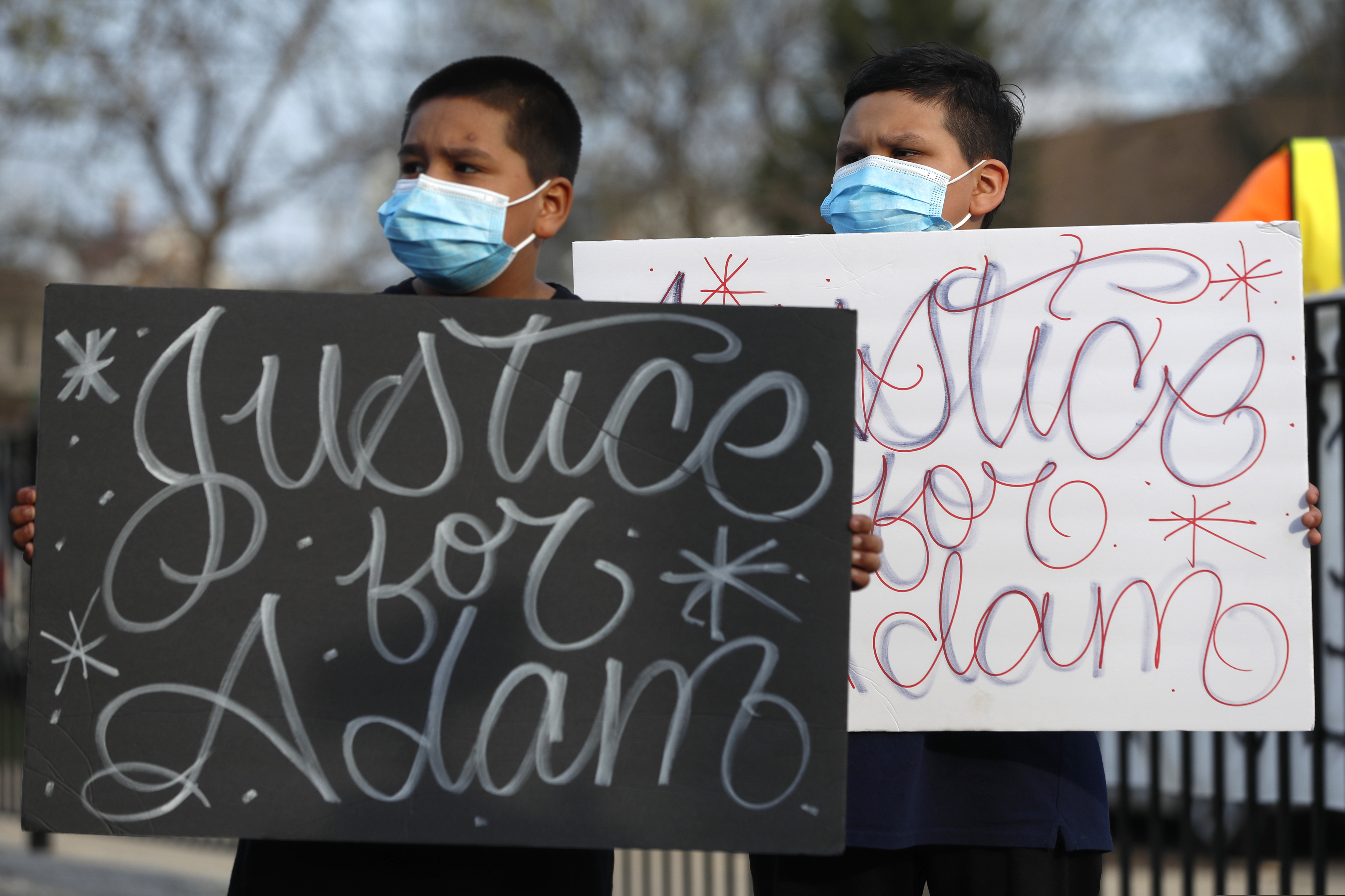 In this April 6 photo, Jacob Perea, 7, left, and Juan Perea, 9, hold signs as they attend a news conference following the death of 13-year-old Adam Toledo, who was shot by a Chicago Police officer at about 2 a.m. on March 29 in an alley.