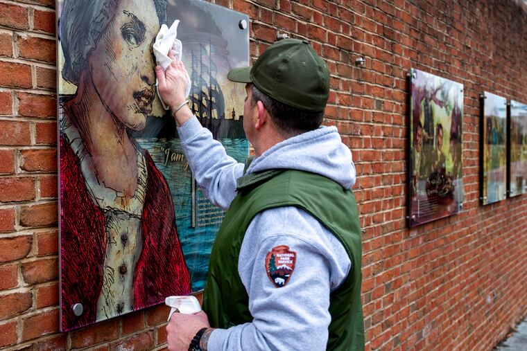A worker cleans the glass panel for Oney Judge after re-hanging it. She was an enslaved woman owned by George Washington, who fled the President’s House on May 21, 1796 for New Hampshire. The panel notes that, “she married, raised a family and lived to old age.”