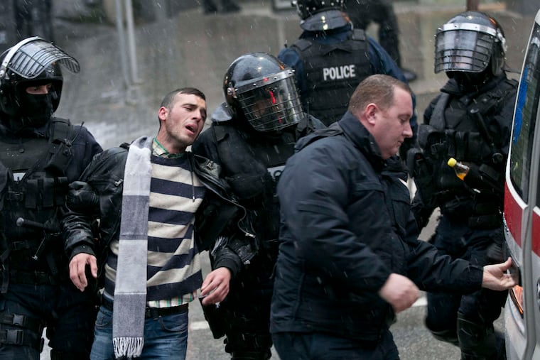 Kosovo police in riot gear detain a supporter of the opposition party during a raidat opposition headquarters in Pristina.