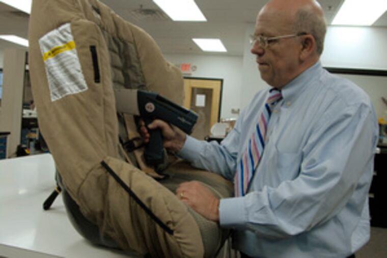 David Brookstein, director of the new Institute for Textile and Apparel Product Safety, examines a car seat with an X-ray fluorescence spectrometer to measure bromine content.