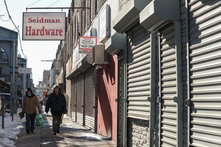 Pedestrians walk past shuttered shops in the Harrowgate neighborhood of Philadelphia.