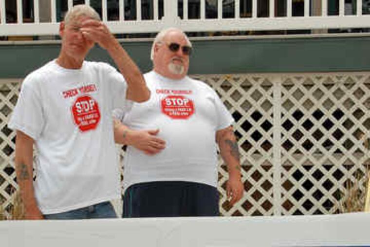 Tavern workers Jim Redmond (left) and Joe Diamond stand behind a display of fraudulent IDs.