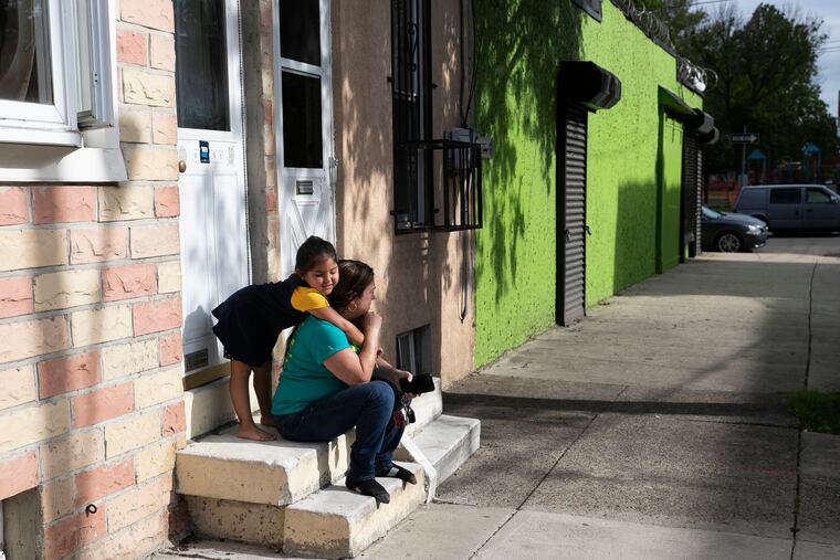 Liv Gonzalez, 4, hugs her grandmother, Paula Hernandez, outside of her home in the Norris Square neighborhood of Philadelphia on Wednesday. Philadelphia released its first property reassessments in three years. Many homeowners are seeing a significant increase.