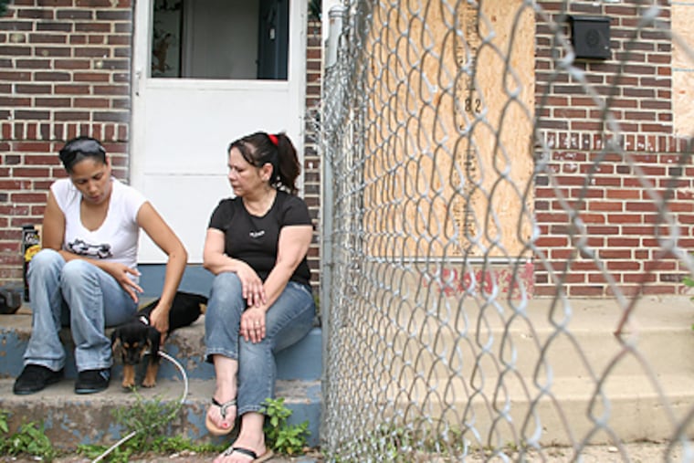 Karen Cortez, 28, and her mother, Nancy Lopez, 53, sit on the front porch of their house in Mount Holly with their puppy, Scooby. (Neal Santos/Inquirer)