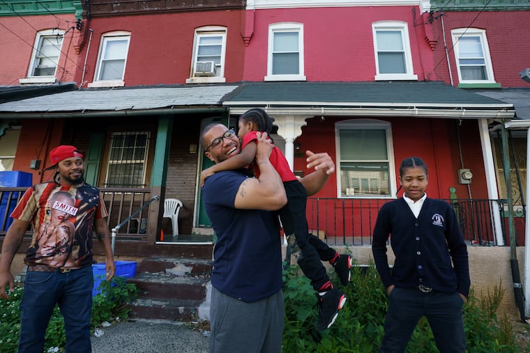 Anthony Thornton, looks on as his brother Terrance Lewis, center, hugs his nephew Sharif Thornton, in West Philadelphia, the day Terrance was released from prison, May 22, 2019.