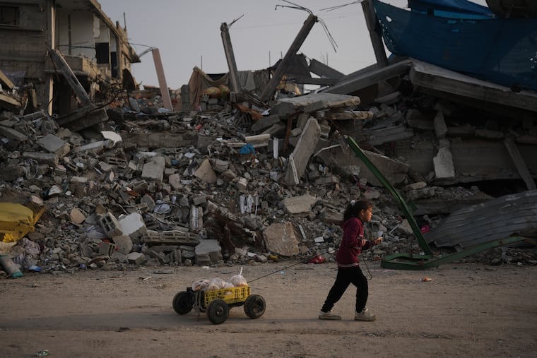 A girl carries bread as she walks past piles of rubble in Gaza City Saturday.