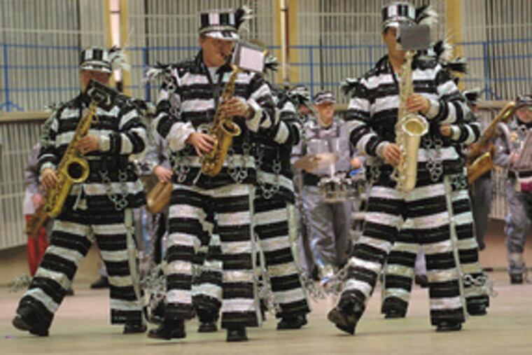 Jailhouse flock: Wearing prison garb, Greater Kensington band members prepare for New Year's. The band's feathery finery comes courtesy of Mummer brethren who helped out after a fire.