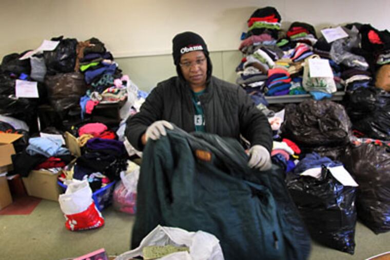 Patrice Hicks sorts through coats, sweaters and other clothes donated for the victims of arson at the Coatesville Community Center last week. (Laurence Kesterson / Staff Photographer)