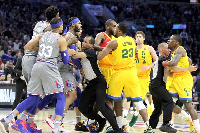 Joel Embiid and Mike Scott of the Sixers are held back by one referee as another holds backs Eric Bledsoe, right, of the Bucks during altercation at Wells Fargo Center during the 1st quarter on April 4, 2019.