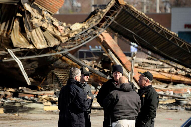 Police investigators meet in front of a burned strip mall in Ferguson. The governor of Missouri said that more than 2,200 National Guard troops would be on the streets late Tuesday to prevent a repeat of the previous night's arson and rioting.