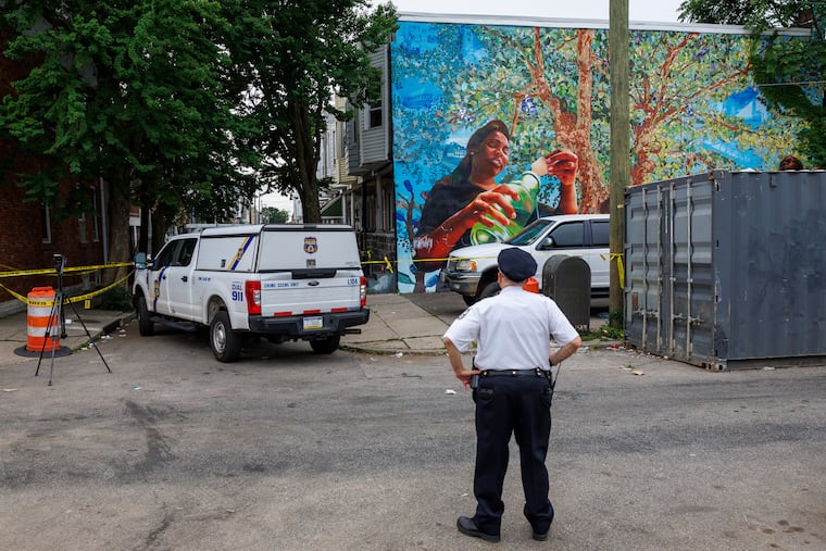 A Philadelphia police officer stands at South Etting and Dickinson Streets following a shooting in July. Nearly a third of PPD officers no longer live in Philadelphia.