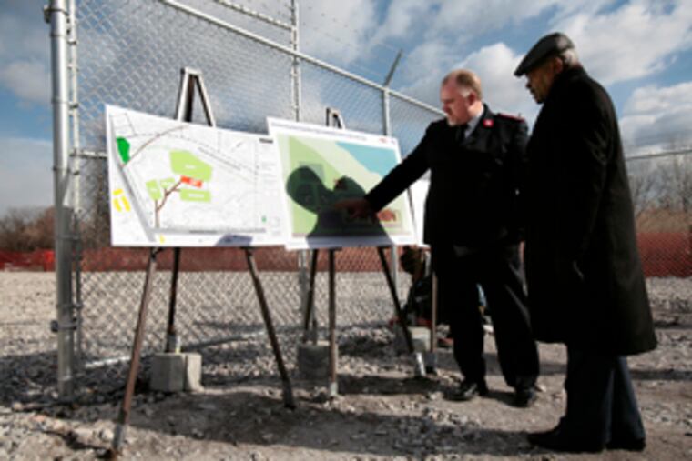 Maj. Paul Cain (left), of the Salvation Army, and Theodore Z. Davis, the city's state-appointed chief operating officer, examine plans for a community center on the landfill site.