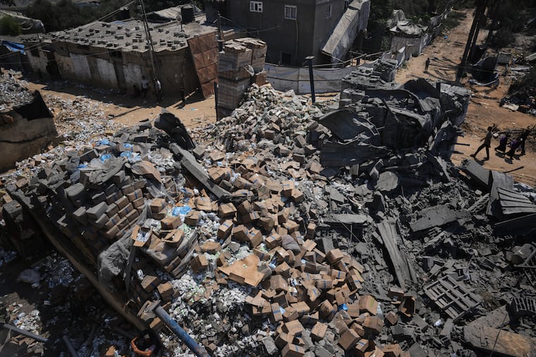 Palestinians walk past a food-aid warehouse damaged in an Israeli airstrike that targeted a nearby house in Deir al-Balah, central Gaza Strip, Wednesday, Aug. 26, 2026.