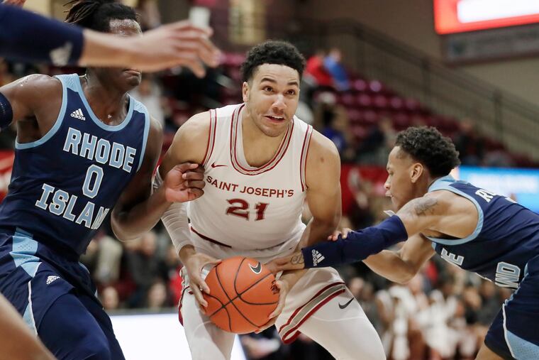 St. Joe’s # 21 Lorenzo Edwards protects the ball from Rhode Island’s # 0 Jermaine Harris and # 1 Fatts Russell in the first half against Rhode Island at Hagan Arena.