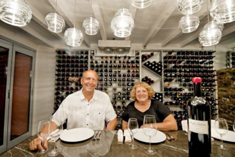 Eric and Lee Miller sit at the table in the climate-controlled wine cellar of their renovated townhouse in West Chester. (CLEM MURRAY / Staff Photographer)