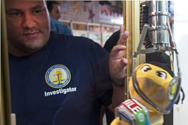 Division of Consumer Affairs Investigator Joseph Chessere, at Schiff's Central Pier, in Atlantic City, demonstrates how crane games are examined. (Abi Reimold / Staff Photographer)