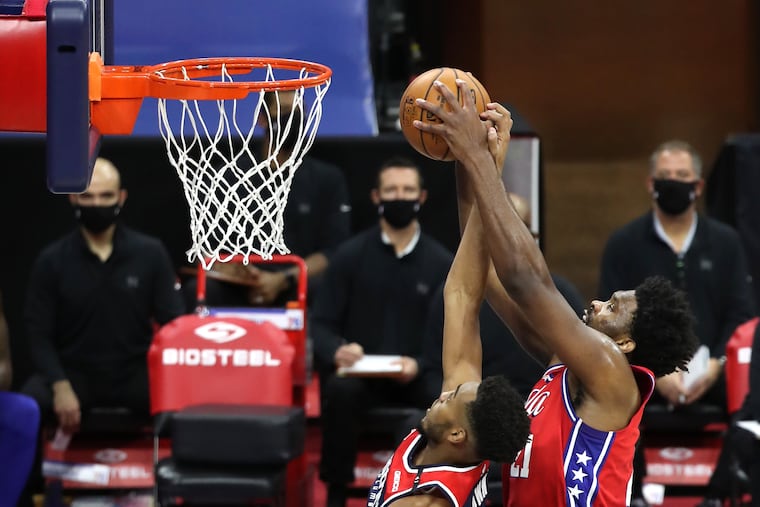 Joel Embiid, right, of the SIxers grabs a rebound over Troy Brown Jr. of the Wizards during the first half of Wednesday's win.