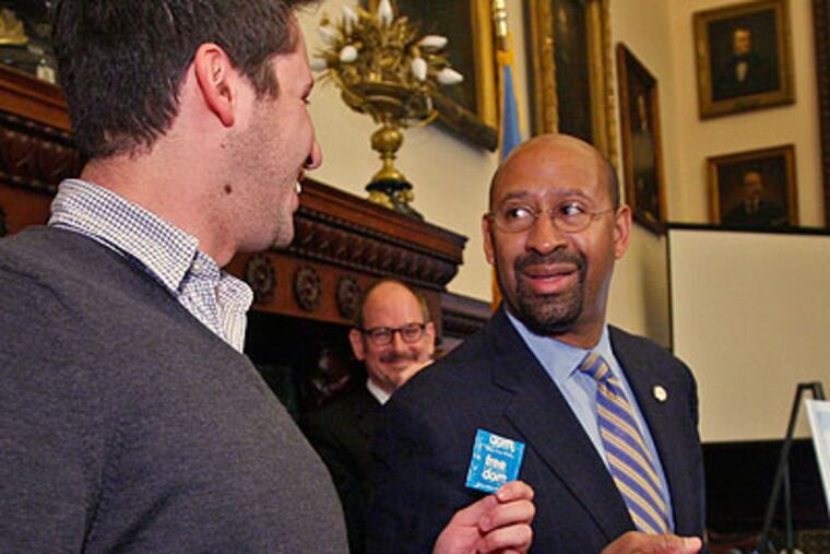 To address the rising STD rates among city youth, Mayor Michael Nutter (right) held a press conference Thursday to unveil a winning condom wrapper design. A sample is being held by winning designer Michael Bodenberger of Philadelphia. (Alejandro A. Alvarez / Staff Photographer)