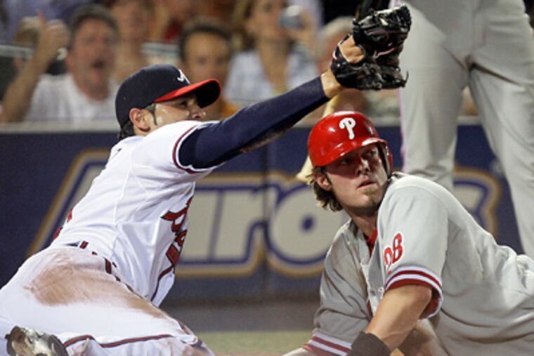 Atlanta Braves relief pitcher Mike Gonzalez, left, and Jayson Werth look for the umpire's call after Werth tried to score from third on a wild pitch in the eighth inning of the Phillies' 5-2 loss on Thursday. Werth was out on the play. (AP Photo/John Bazemore)