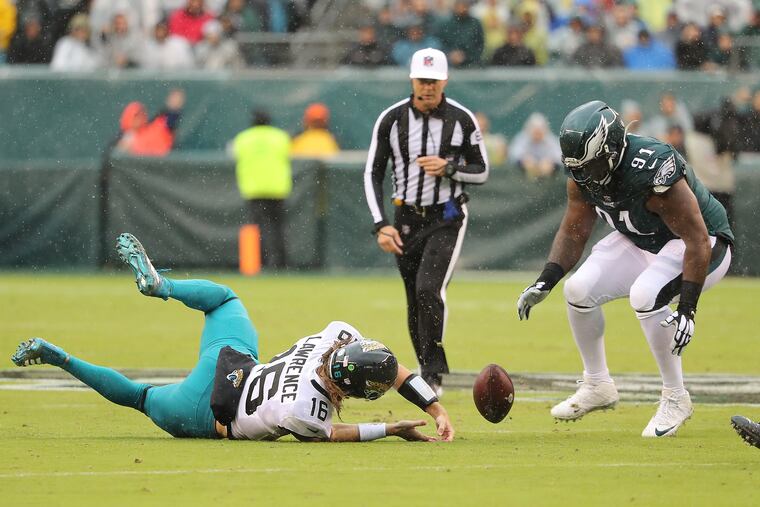 Jacksonville Jaguars quarterback Trevor Lawrence (left) fumbles the football as Eagles defensive tackle Fletcher Cox (right) prepares to fall on it during the second quarter.